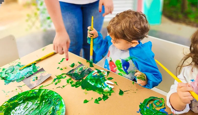 Criança pintando em proposta de arte na Educação Infantil bilíngue